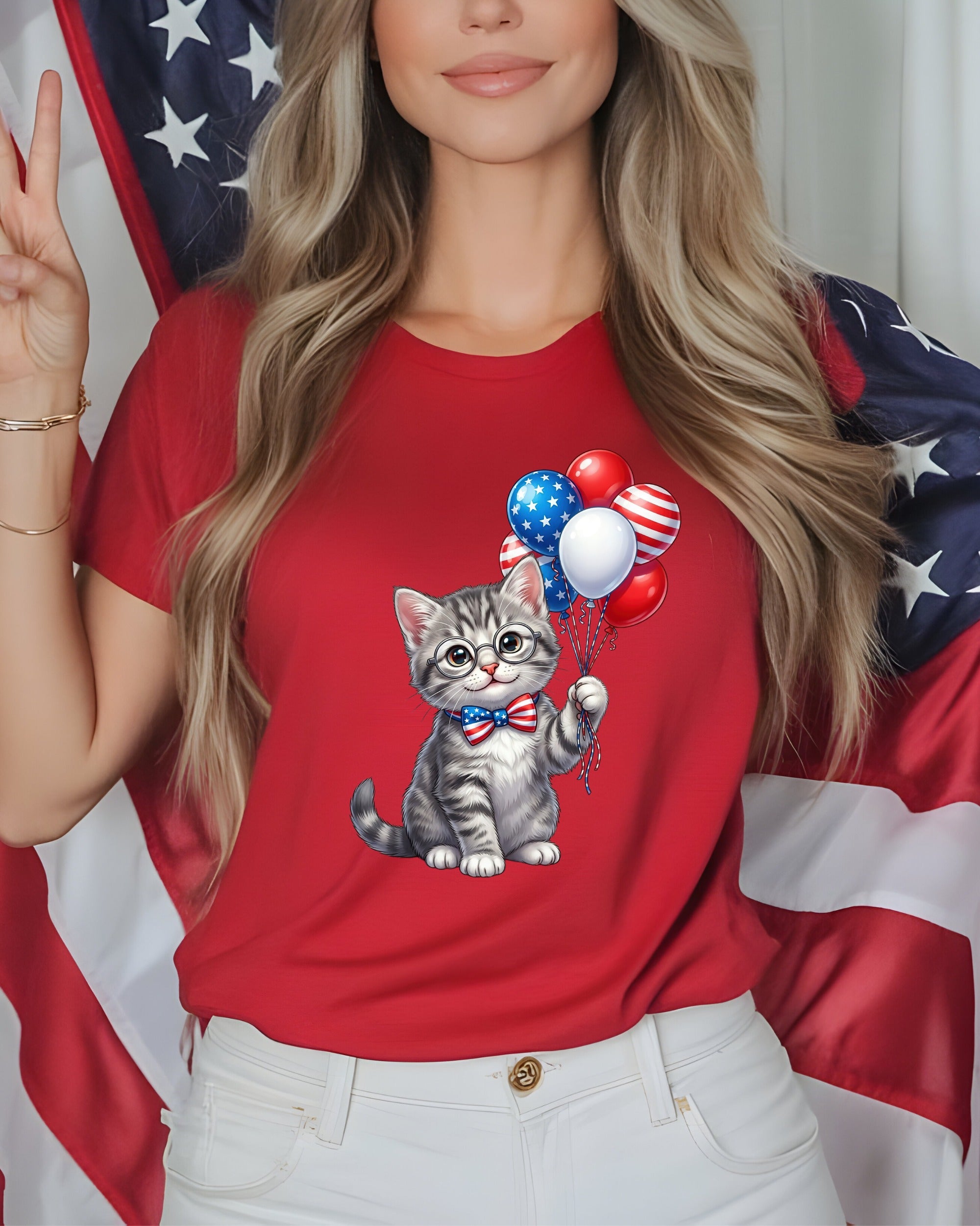Cat in bowtie holding balloons with US flag behind on red t-shirt.
