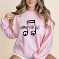 Pink sweatshirt with "HARMONY AT THE PLATE" musical note graphic.