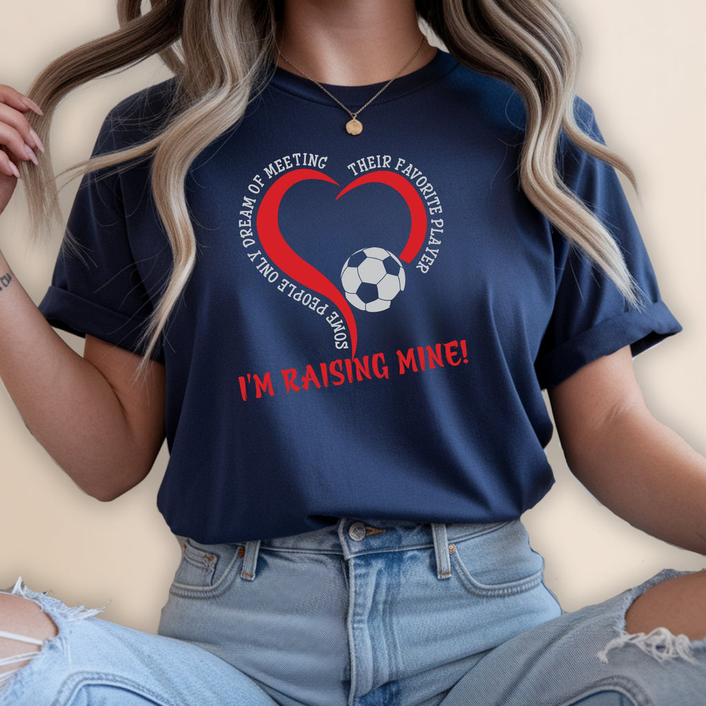 Navy t-shirt with a heart graphic and soccer ball; text says "Some People Only Dream of Meeting Their Favorite Player I'm Raising Mine!"