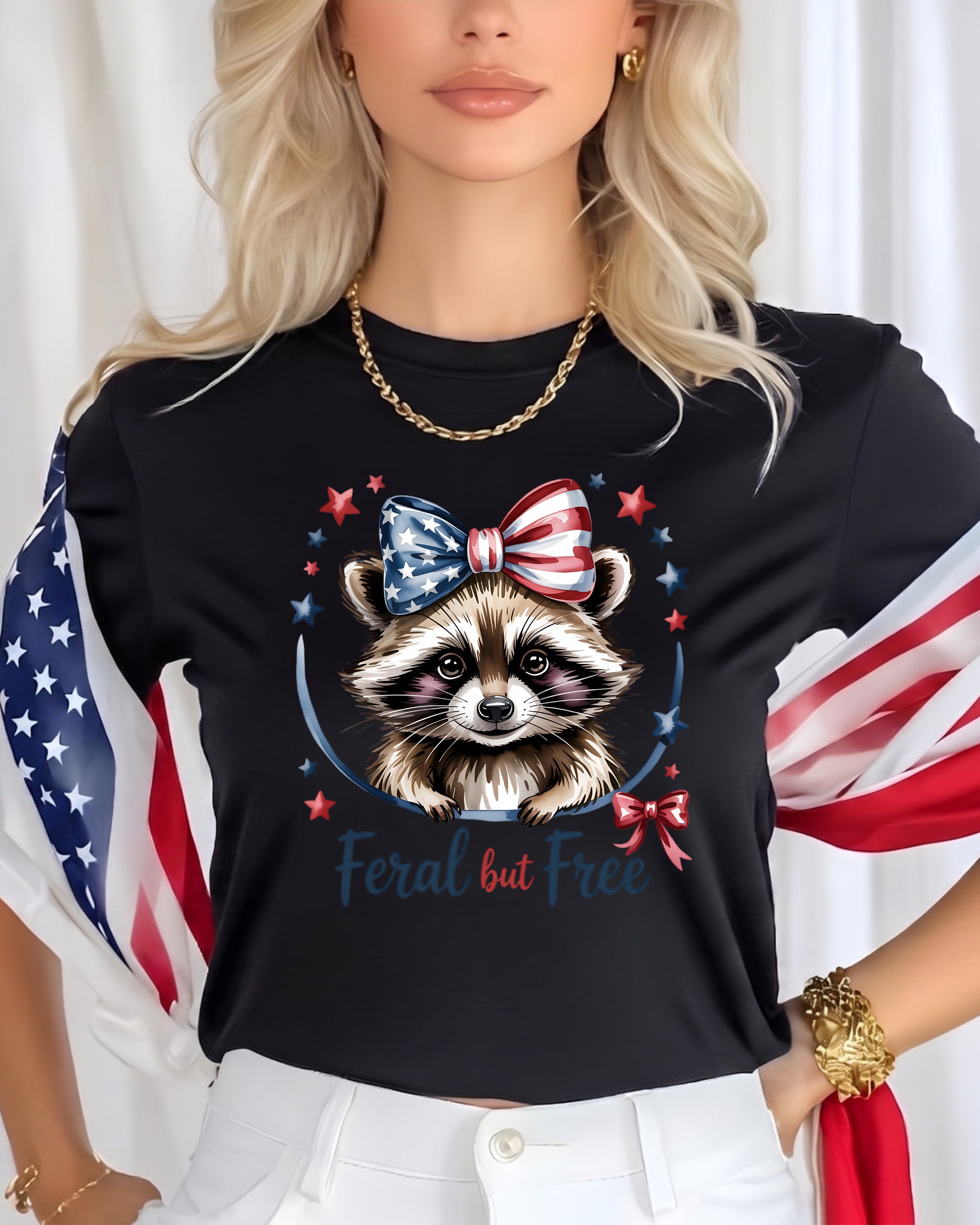 Black t-shirt with raccoon wearing patriotic bow, "Feral but Free" text.