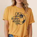Yellow t-shirt with black graphic of a soccer ball and text "I'll always be your biggest fan".