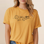 Yellow t-shirt with a line drawing of a soccer ball, bow, and cleats.