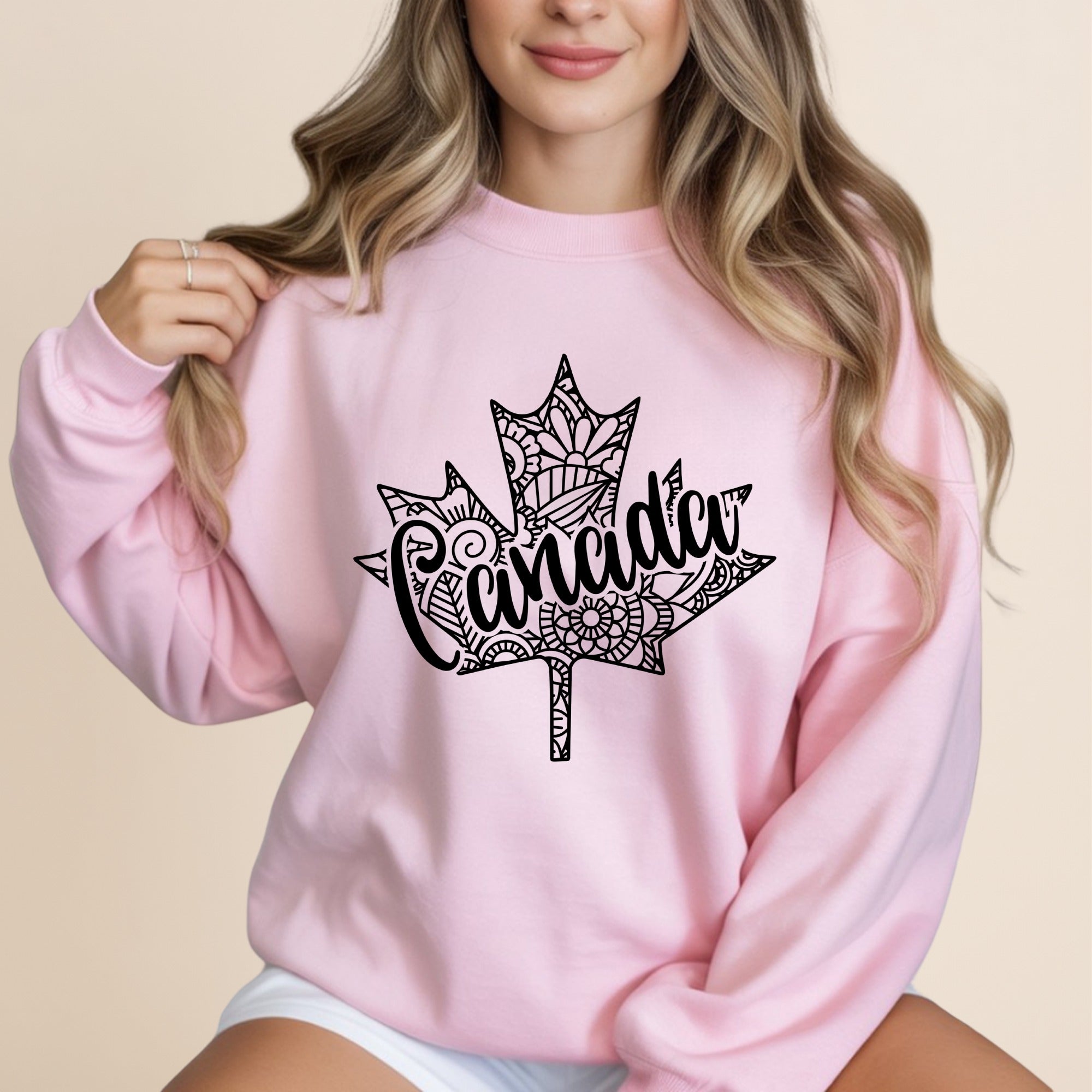 Pink sweatshirt with a black maple leaf design with "Canada" in the center.