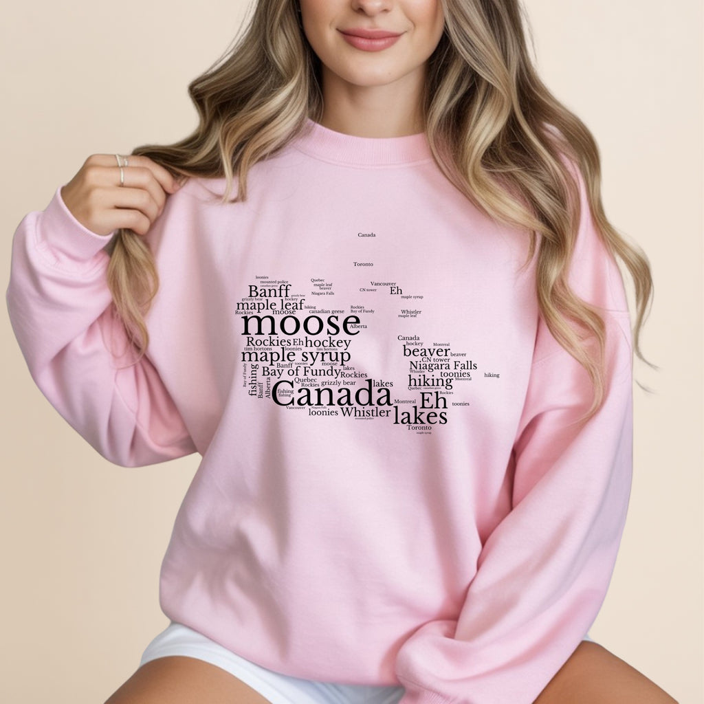 Pink sweatshirt with "Canada" shaped word cloud, featuring Canadian landmarks and words.