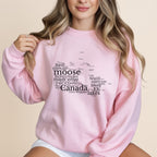 Pink sweatshirt with "Canada" shaped word cloud, featuring Canadian landmarks and words.
