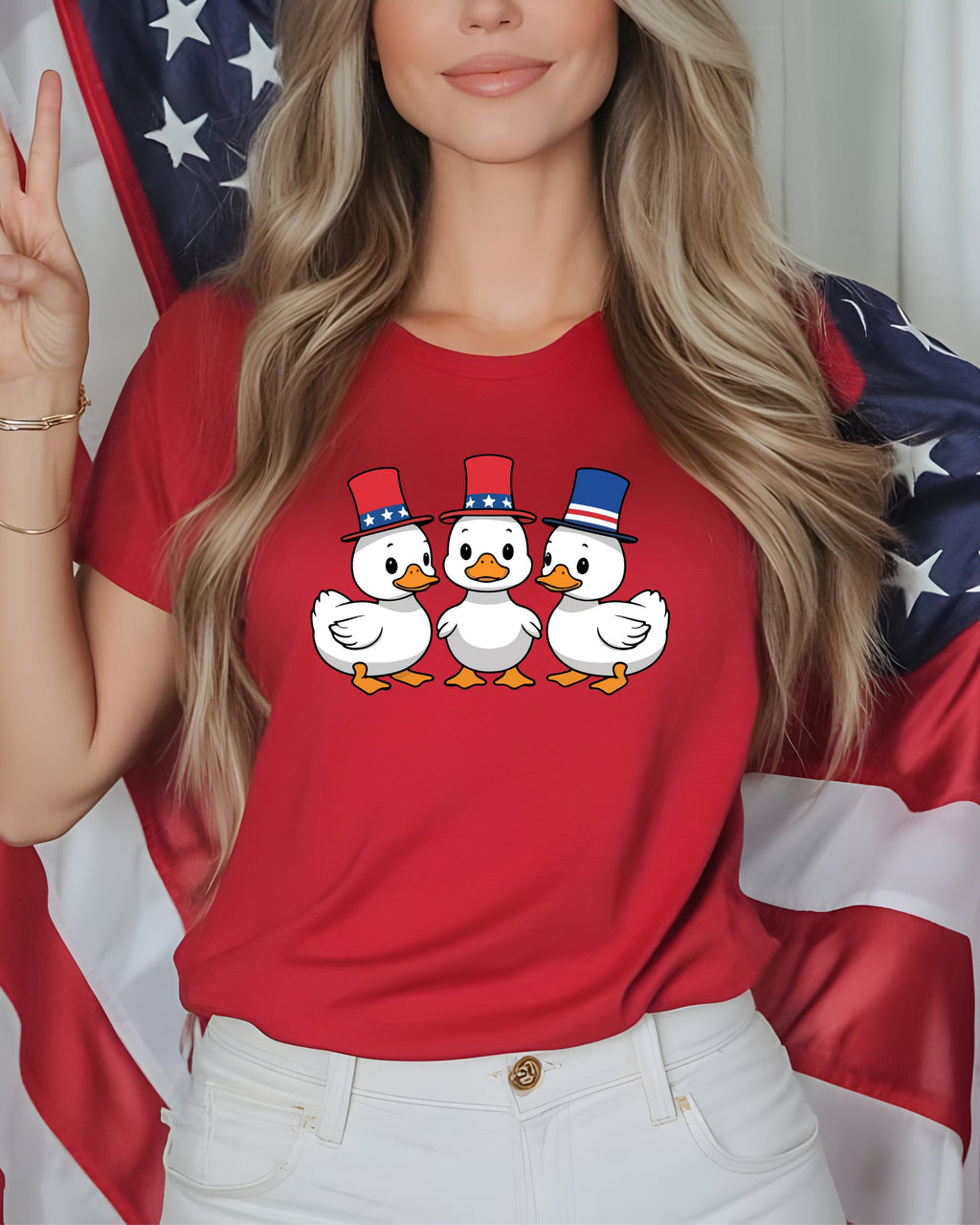 Three cartoon ducks in red, white, and blue hats on a red t-shirt.
